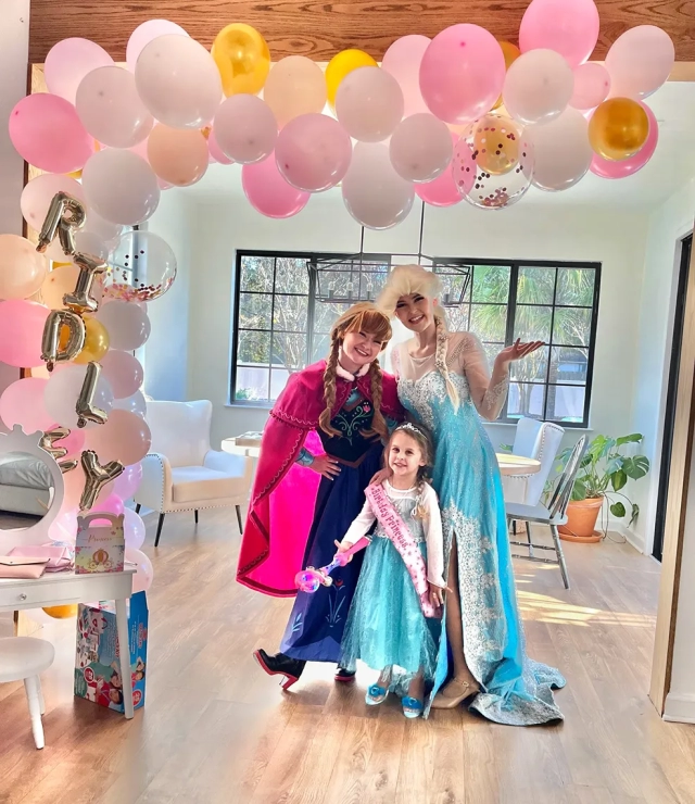 anna and elsa party with a little girl under balloon arch