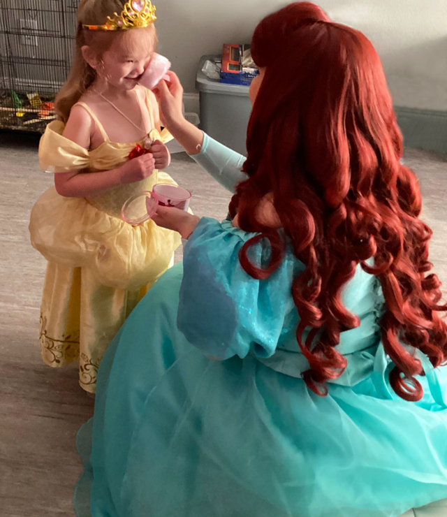 princess ariel applying magical face glitter to little girl
