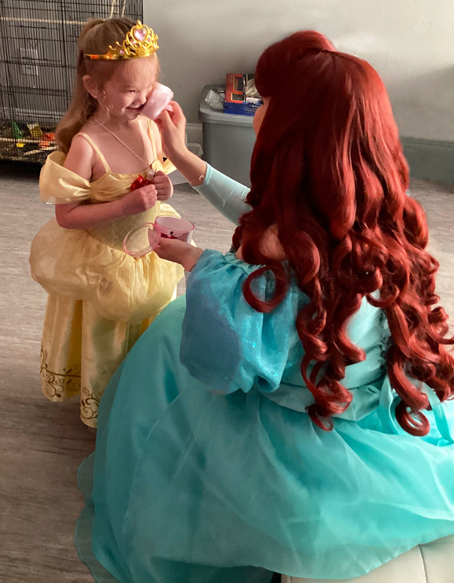 princess ariel applying magical face glitter to little girl