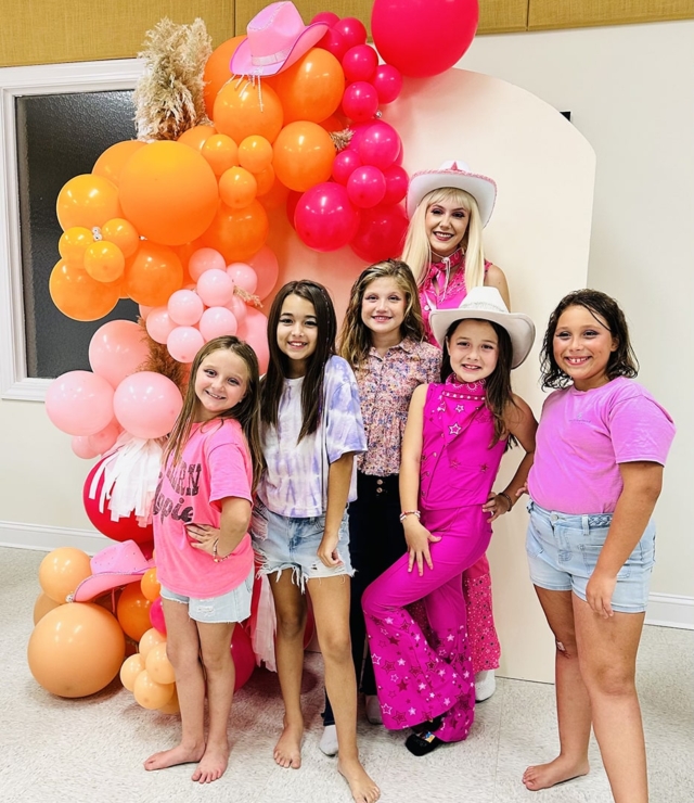 fashion doll posing with girls at a birthday party