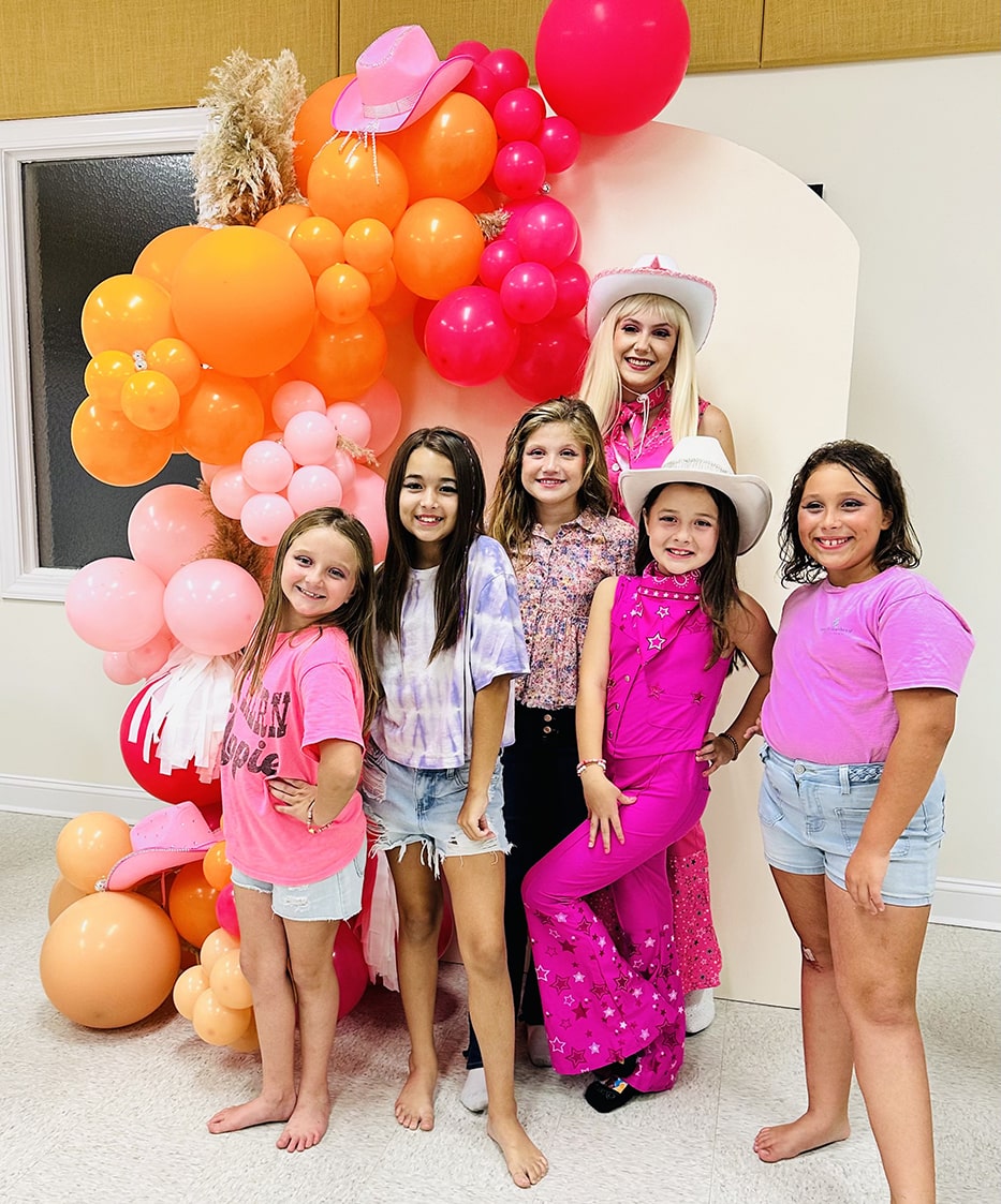fashion doll posing with girls at a birthday party